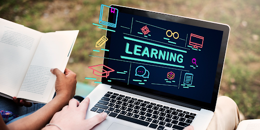 A person holding a laptop with learning text shown on the screen.